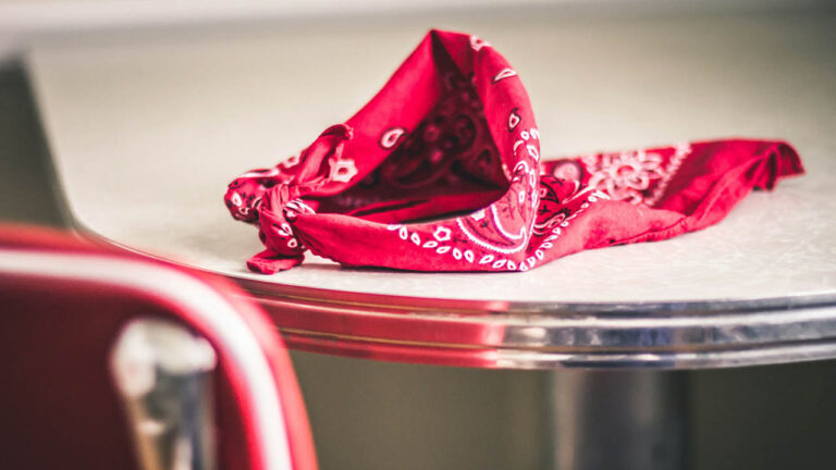 Red patterned bandana tied in a knot, resting on a wooden table.