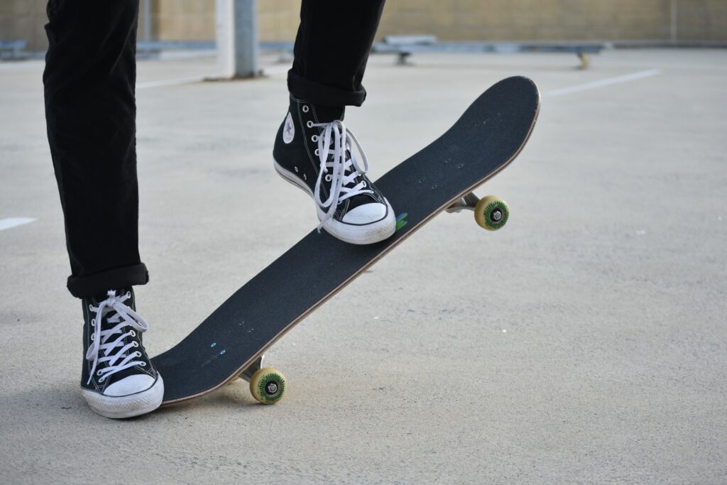 A skateboarder in black All Star sneakers with white laces.