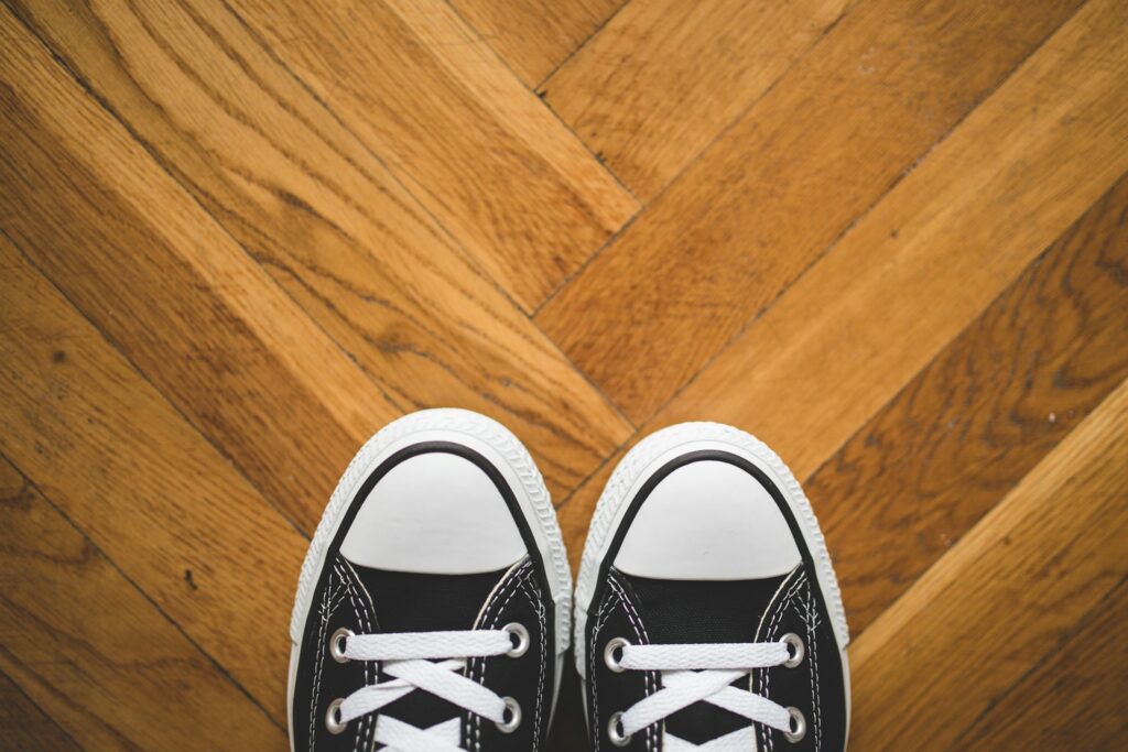 Classic Converse sneakers on a parquet floor.